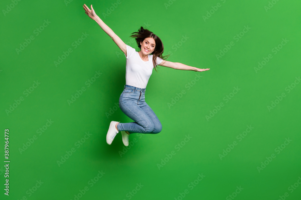 Full size photo of cheerful girl jump hold hands plane fly game concept isolated over green color background Full size photo of cheerful girl jump hold hands plane fly game concept isolated over green color background