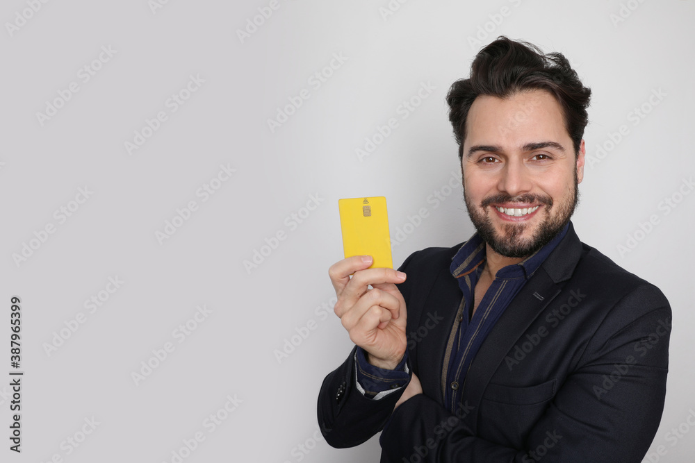 Excited happy young man posing isolated over white wall background holding credit card. Excited happy young man posing isolated over white wall background holding credit card.