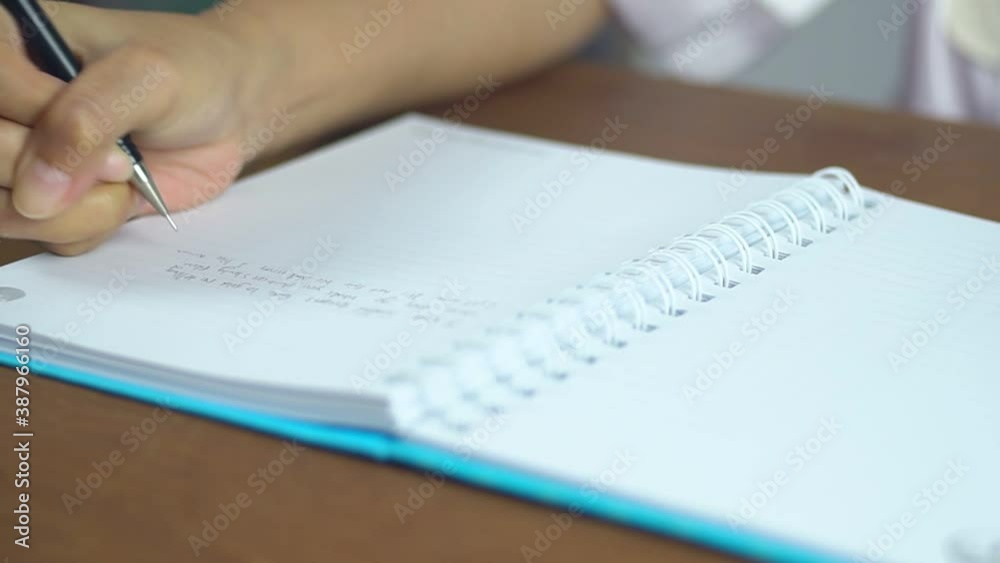 A woman with a mechanical pencil and writing.Female hand writing in notebook. A woman with a mechanical pencil and writing.Female hand writing in notebook.