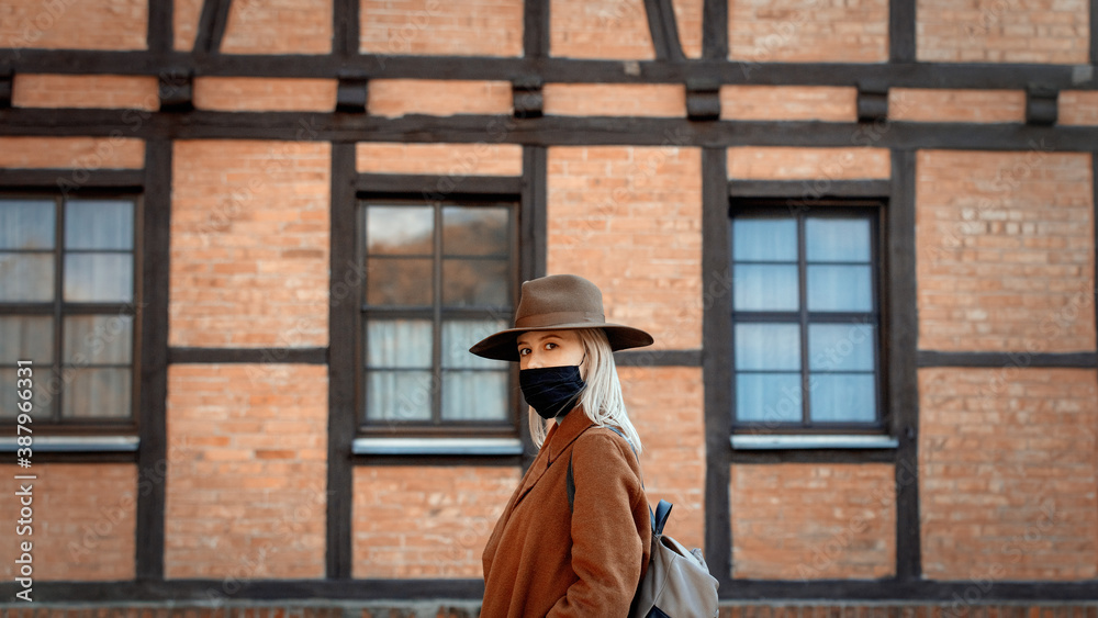 Style woman in hat and face mask with timber house on background