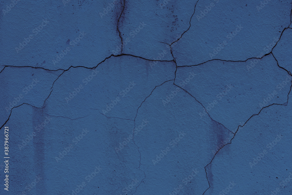 Fototapeta premium Texture of a wall covered with dark blue aged plaster. There are cracks on the surface of plaster
