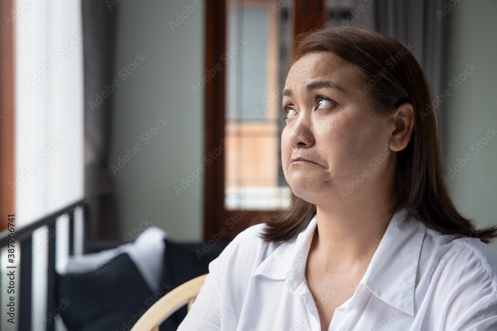 unhappy asian middle aged woman looking up unhappy asian middle aged woman looking up