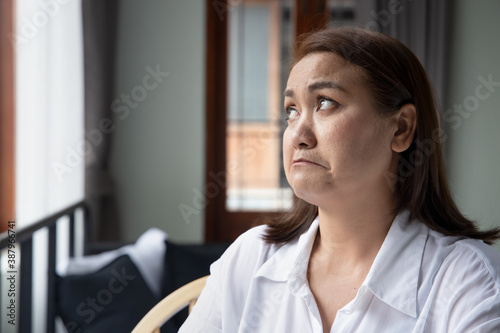 unhappy asian middle aged woman looking up