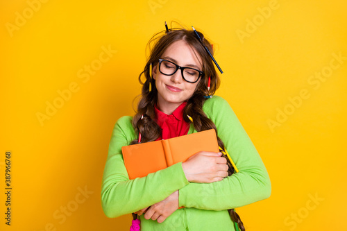 Close-up portrait of attractive funky dreamy cheery teenage girl hugging exercise book literacy isolated over shine yellow color background