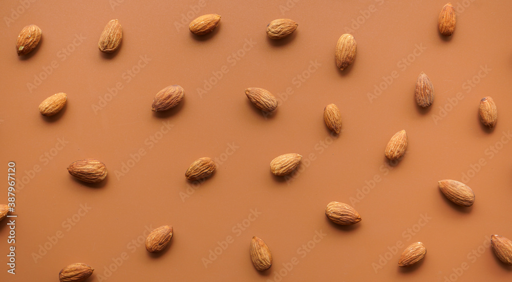 pattern of almonds arrange on brown background pattern of almonds arrange on brown background