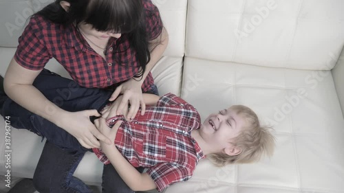 happy family little boy laughs from tickling mother. woman playing with son a happy family laughing lifestyle indoors