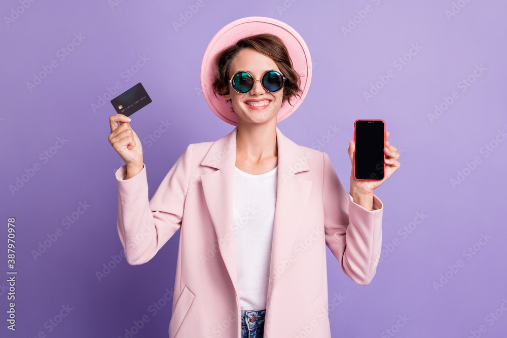 Photo of nice cute young lady wear sunglasses cap jacket hold telephone credit card isolated on violet background