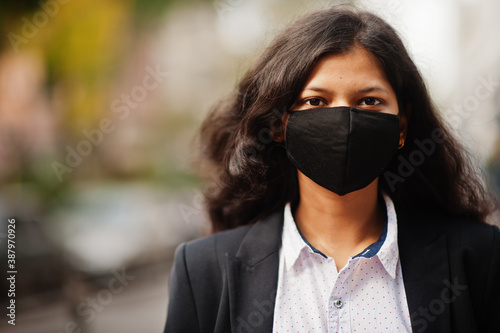 Gorgeous indian woman wear formal and black face mask, posing at street during covid pandemia.