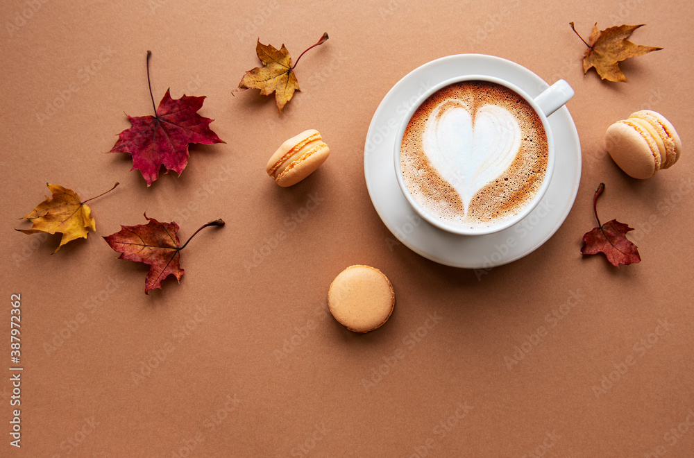 Cup of coffee and dry leaves on brown background - obrazy, fototapety, plakaty 