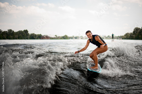 Active cheerful woman riding on the wake surf on the bending knees