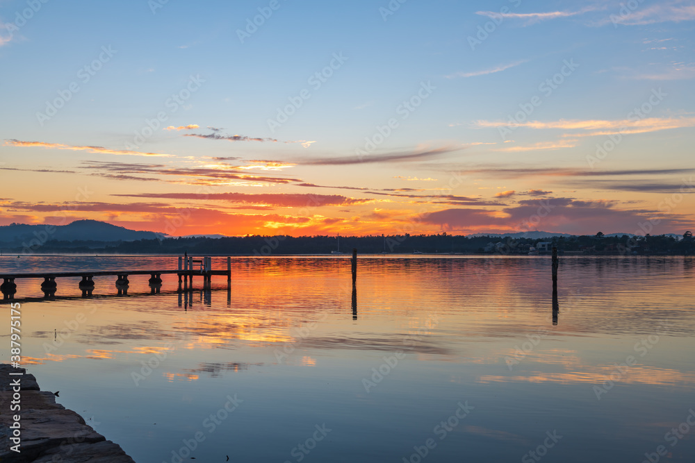 Fototapeta premium Clouds, reflections and sunrise over the bay