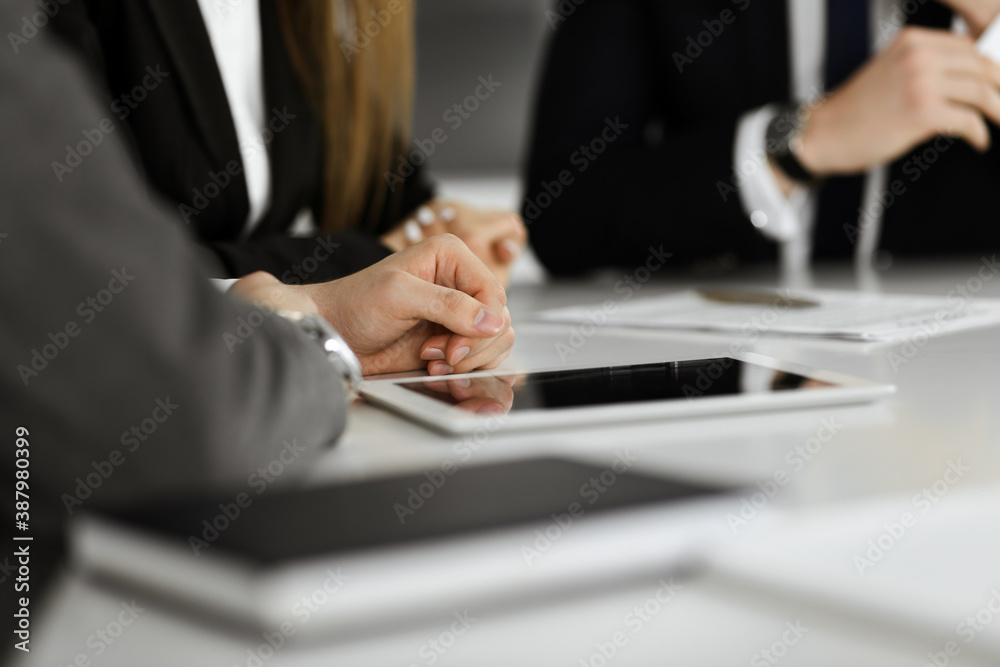 Unknown businessmen and woman sitting, working and discussing questions at meeting in modern office, close-up