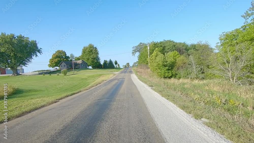 POV driving on county road with no center line past maturing fields and large farmyards in rural Iowa on a sunny early autumn day - near Kalona, Iowa, USA POV driving on county road with no center line past maturing fields and large farmyards in rural Iowa on a sunny early autumn day - near Kalona, Iowa, USA