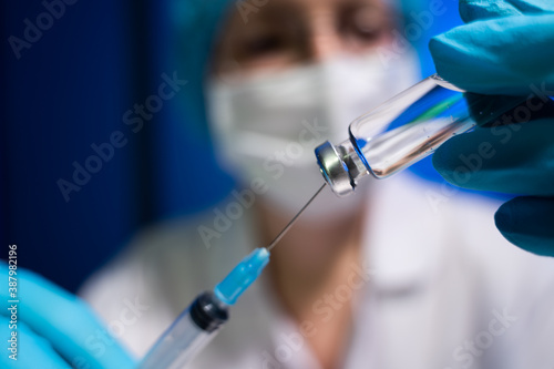 Female doctor working with syringe needle and ampoule of medicine.