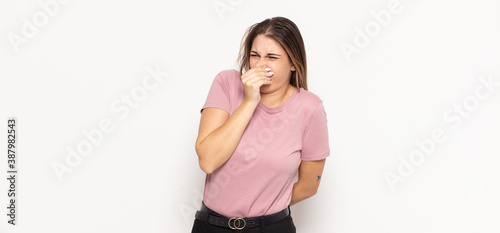 young blonde woman feeling disgusted, holding nose to avoid smelling a foul and unpleasant stench