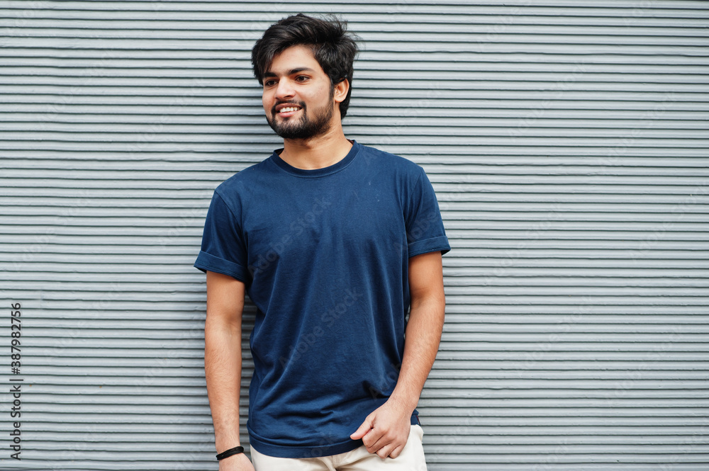 Stylish casual indian man wear blue t-shirt posing against grey wall. - obrazy, fototapety, plakaty 
