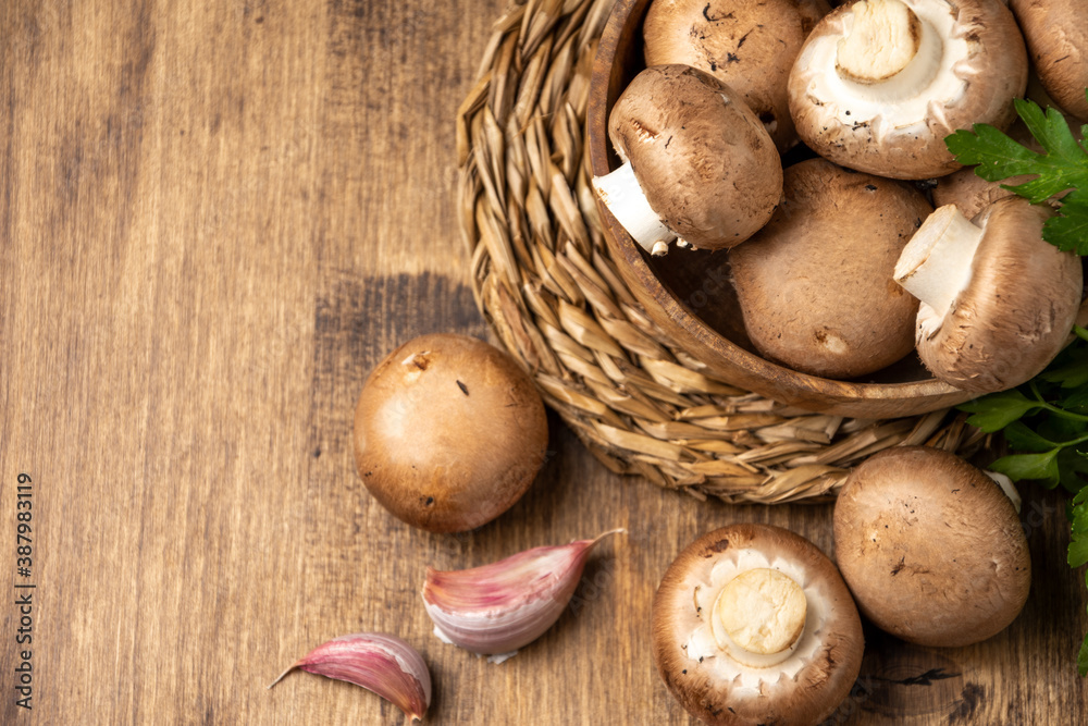 Top view of portobello mushrooms in wooden bowl with parsley and garlic on rustic wooden table, horizontal, with copy space Top view of portobello mushrooms in wooden bowl with parsley and garlic on rustic wooden table, horizontal, with copy space