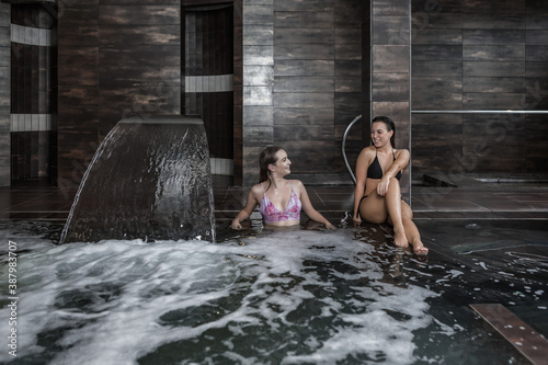 Cheerful women getting hydro massage in spa center