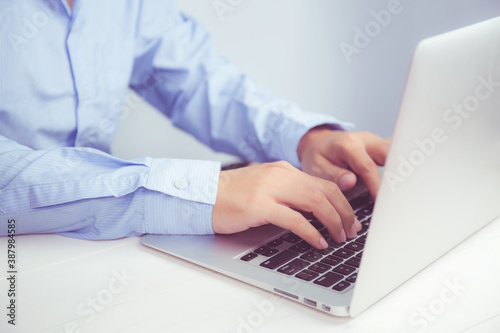 Hand of young man working on laptop computer on table at home office  male typing keyboard notebook on desk  businessman surfing to internet online or check mail  business and communication concept.