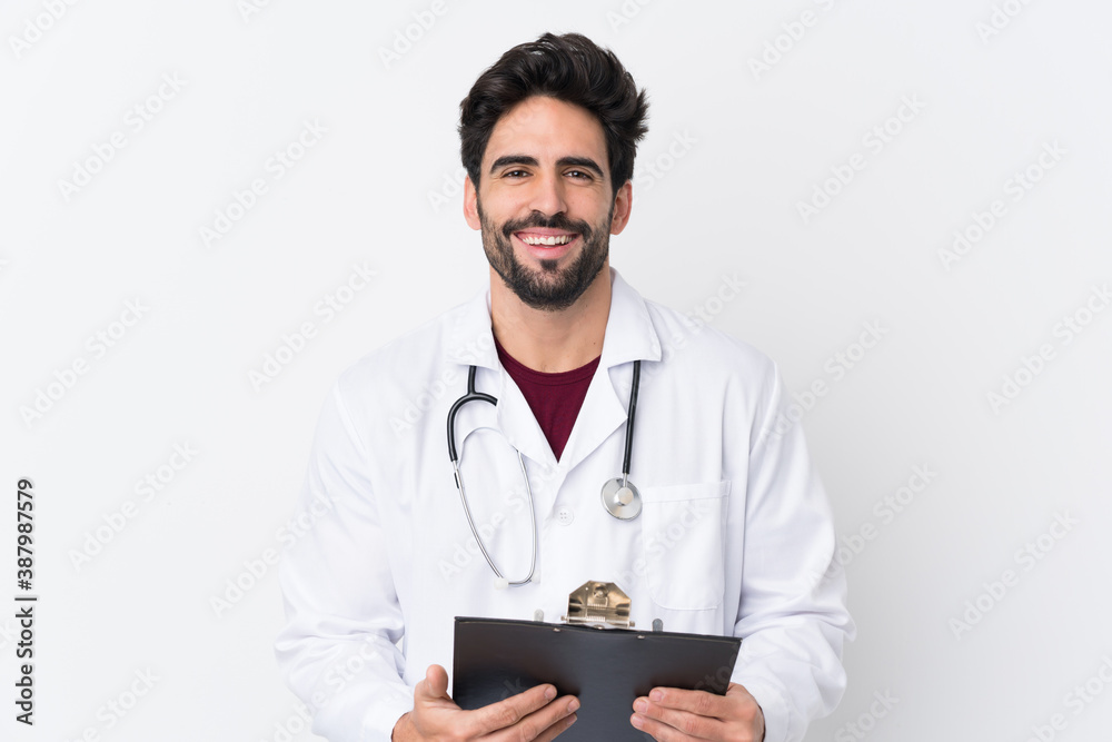 Young handsome man with beard over isolated white background wearing a doctor gown and holding a folder Young handsome man with beard over isolated white background wearing a doctor gown and holding a folder