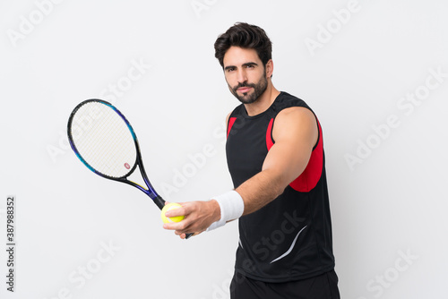 Young handsome man with beard over isolated white background playing tennis © luismolinero