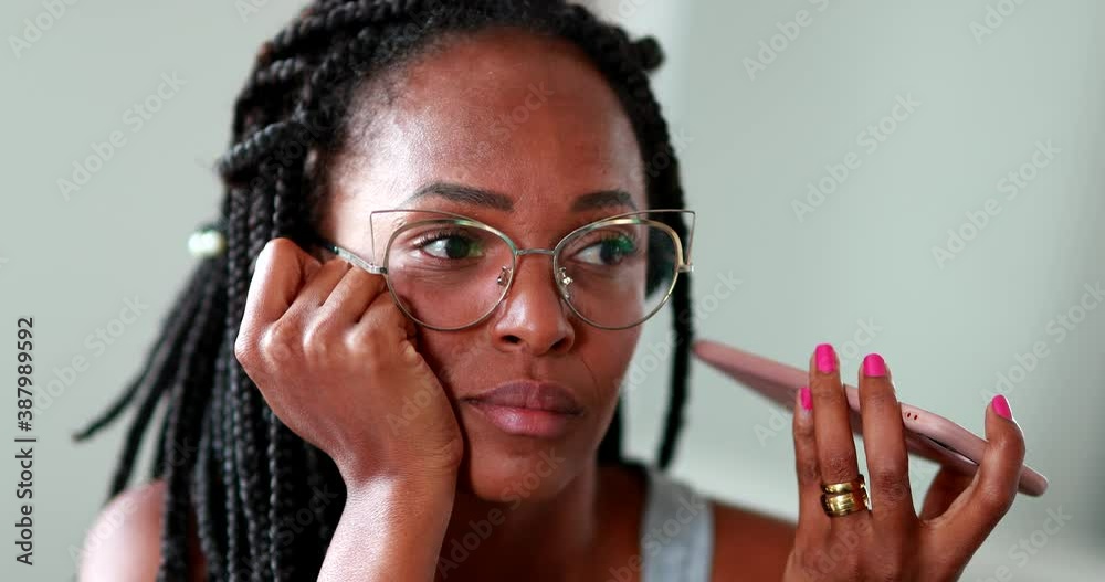 Black woman listening to voice message on cellphone, African person sending voice message on smartphone