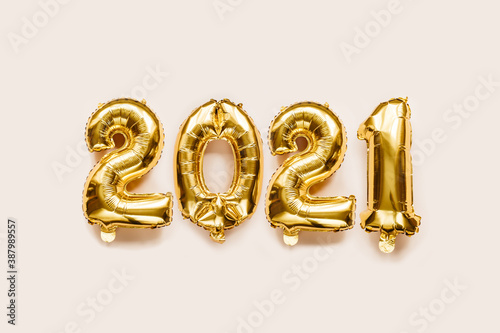 Gold foil balloons numeral 2021 on beige background. Merry Christmas and happy new year concept. Flat lay, top view, copy space