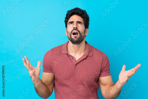 Young handsome man with beard over isolated blue background frustrated by a bad situation