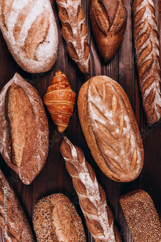 Various types of Bakery bread - fresh rustic crusty loaves of bread and baguette on white background. (top view, flat lay).