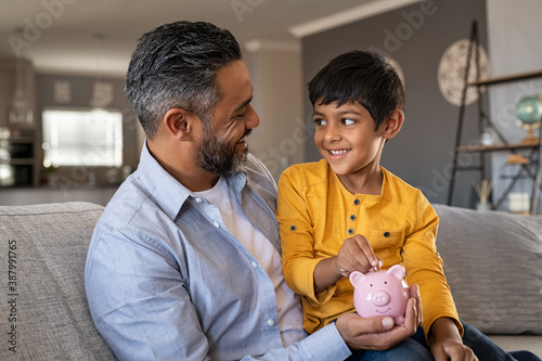 Child sitting on father lap while saving money