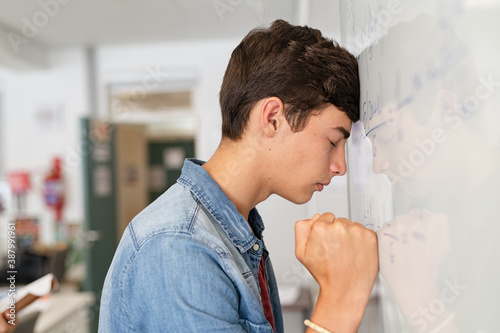 Stressed high school student having difficulty solving the equation at white board