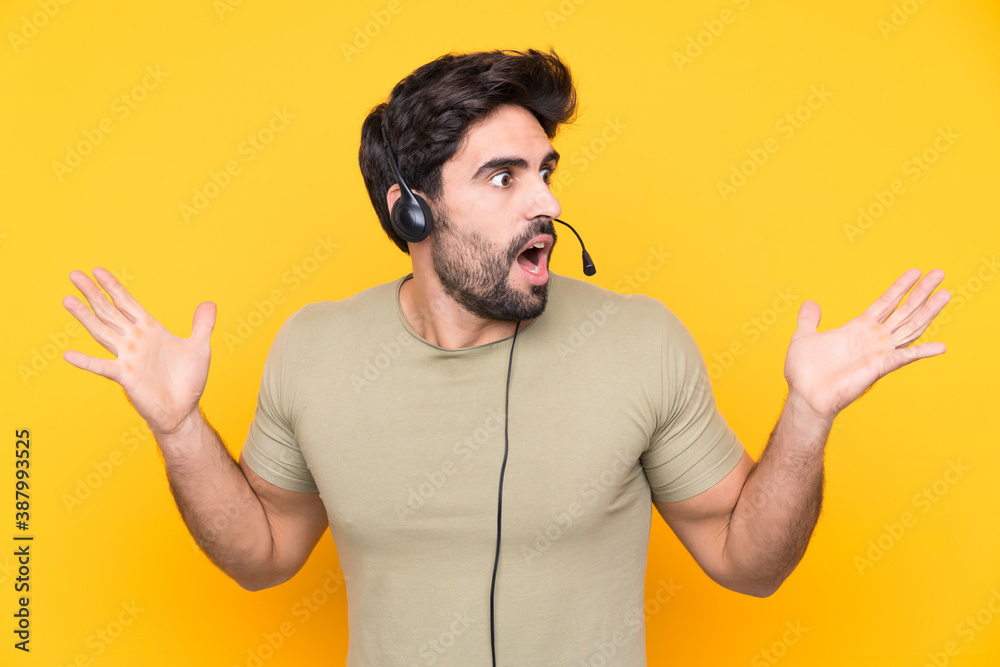 Telemarketer man working with a headset over isolated yellow background with surprise facial expression Telemarketer man working with a headset over isolated yellow background with surprise facial expression