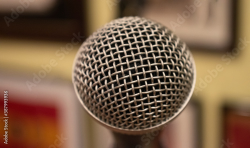 Close up on a metal microphone, with a blurry background