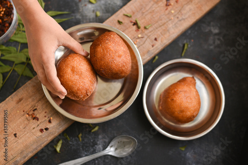 Sweet Bonda , Vellam Bonda , girl hand take Banana Bonda fritters Undan Pori Kerala tea time snack with whole wheat flour sweet food made with grated coconut in India. Bajji bonda Indian Street Food