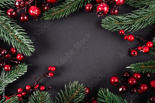 Top view of red artificial berries and pine branches on black background  new year concept