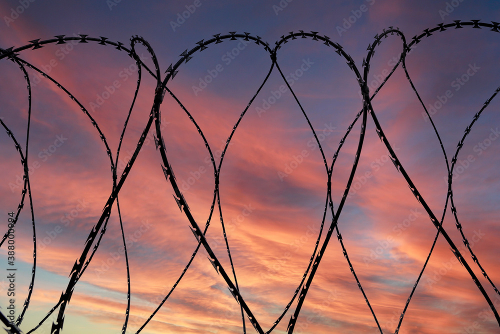 Barbed wire on dramatic sky background at sunset Barbed wire on dramatic sky background at sunset