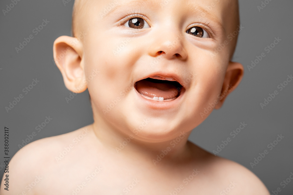 Adorable baby boy showing his first teeth, concept of caring for baby teeth, dental care Adorable baby boy showing his first teeth, concept of caring for baby teeth, dental care