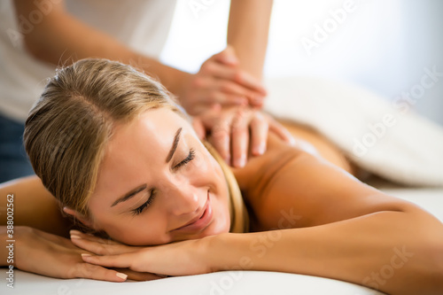 Professional masseur doing therapeutic massage. Woman enjoying massage in her home. Young woman getting relaxing body massage.
