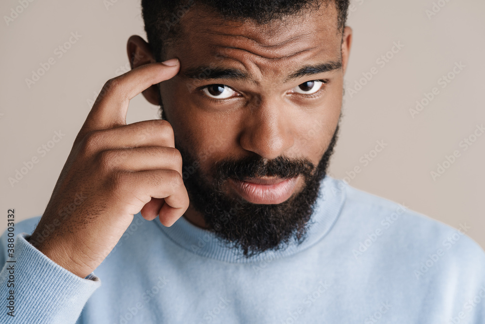 Confused african american guy pointing finger at his head Stock-Foto