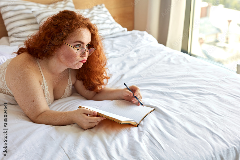 charming dreamy woman with natural red hair thinking, writing in diary, notebook while having rest at home, good times for new ideas charming dreamy woman with natural red hair thinking, writing in diary, notebook while having rest at home, good times for new ideas