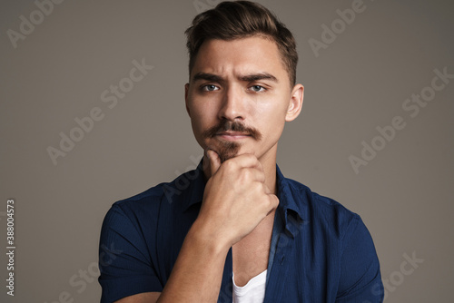 Image of puzzled unshaven guy posing and looking at camera