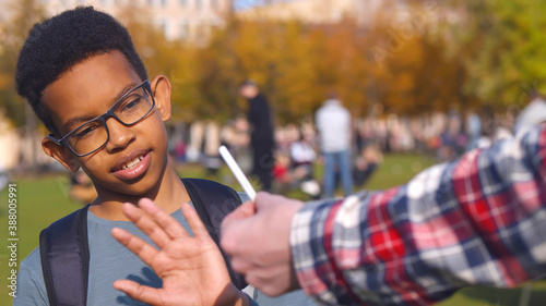 African preteen boy refusing cigarette offered by dealer outdoors