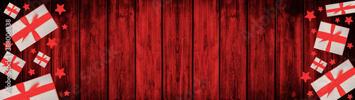 Festive Christmas / Advent background banner panorama - Top view / above view from gift boxes with red ribbon and stars, on rustic red wooden boards, wood table texture 