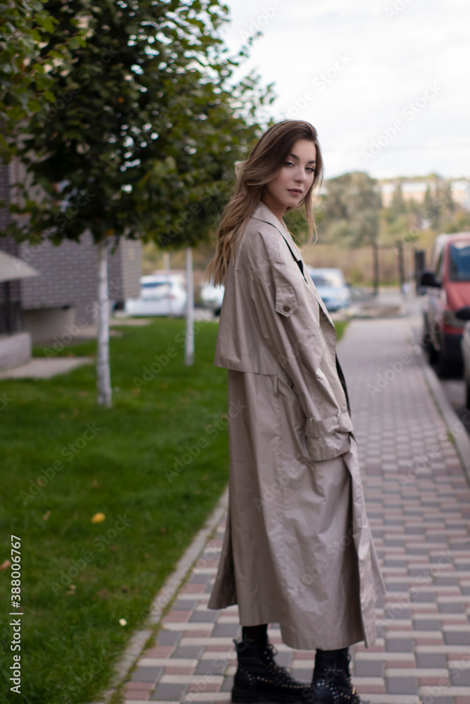 attractive slim young brunette in fashionable trench coat and black dress.