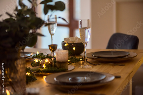 A glass of champagne in the background of the Christmas table and the lights of the Christmas tree