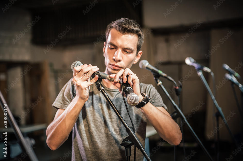 Theater audio technician adjusting an microphones on the scene. Installing and testing the sound system in the background