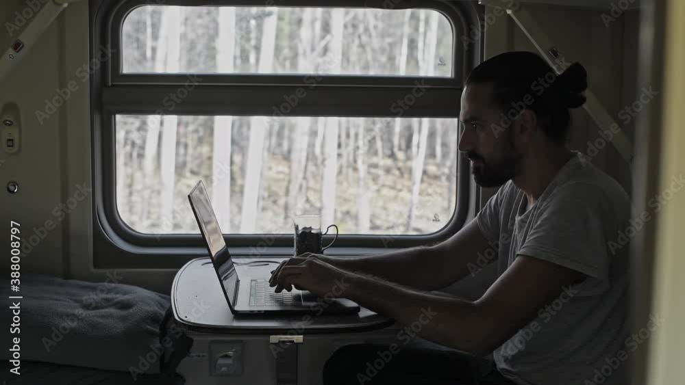 The man on the train is working on the computer. Prints text on laptop keyboard. The man on the train is working on the computer. Prints text on laptop keyboard.