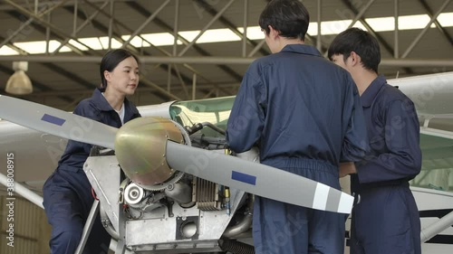 Group of young asian aviation maintenance engineer doing a pre flight checkup or maintenance on a small engine aircraft using digital tablet in hangar. Transportation and Technology concept. photo