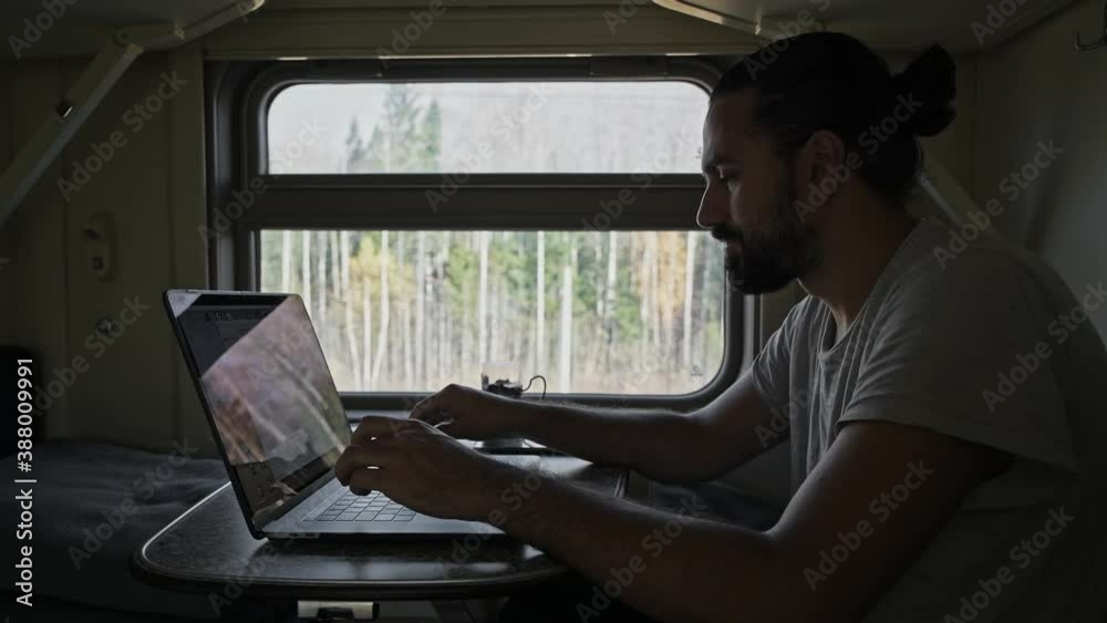 The man on the train is working on the computer. Prints text on laptop keyboard. The man on the train is working on the computer. Prints text on laptop keyboard.