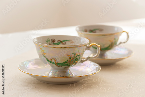 Two gold decorated tea cups built by a consecrated tablecloth.